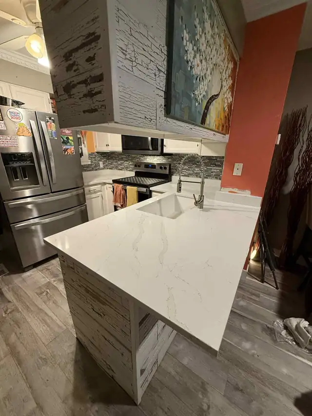 Kitchen with new white quartz countertop and undermount sink beside stainless refrigerator