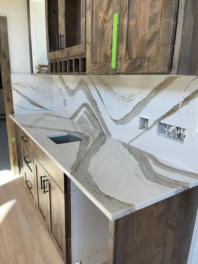 White quartz with bold gray veining running from countertop up a full-height backsplash with two niches