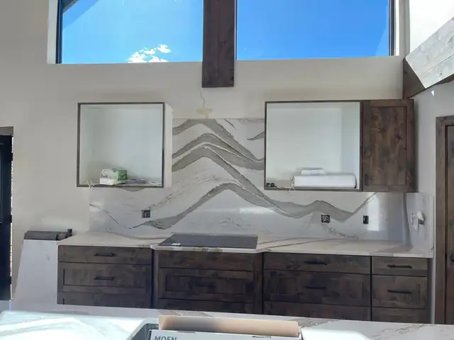 Wide veined stone backsplash between open shelving over dark wood base cabinets