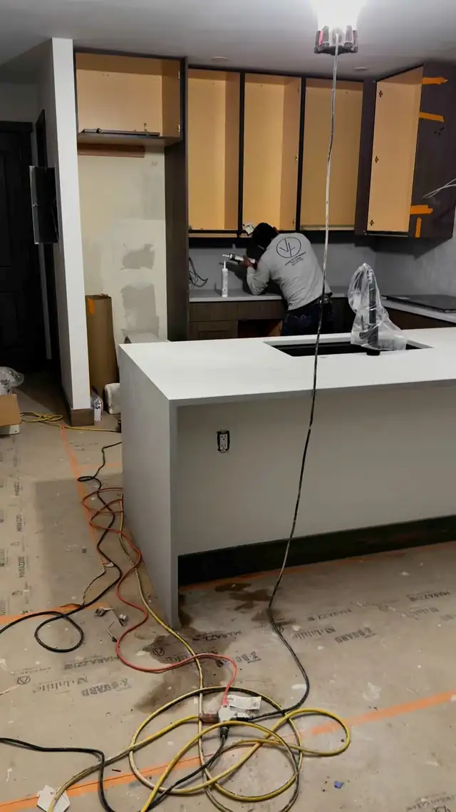 VL installer working at the sink cut-out of a white quartz waterfall island during installation